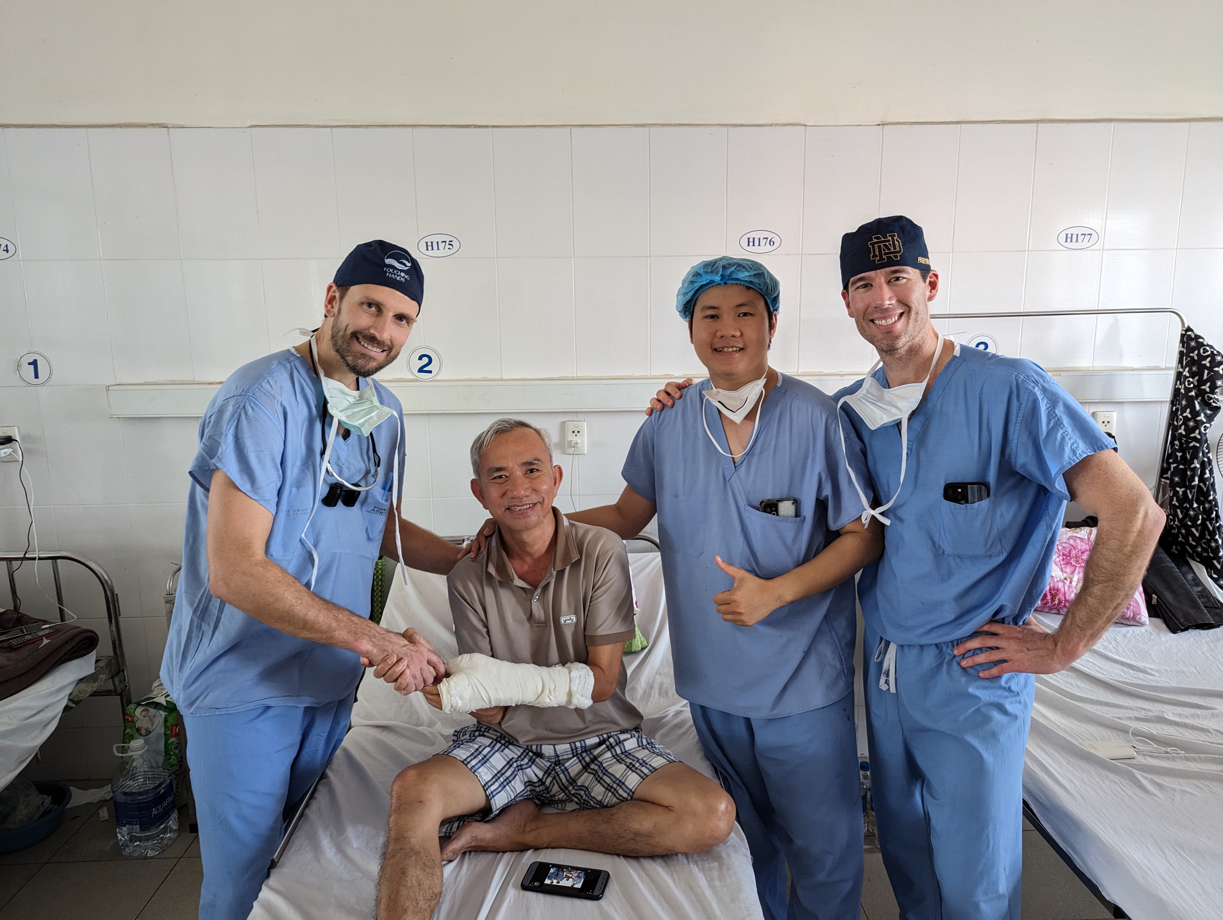 Surgeons and a patient smiling at camera.
